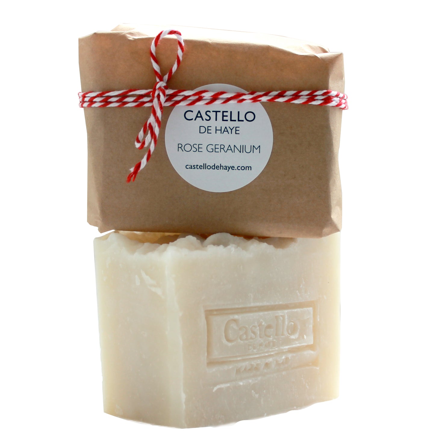 A bar of soap with 'Castello de Haye' engraved on it, wrapped in brown kraft paper with a red and white twine, and a label on top that reads 'ROSE GERANIUM'.