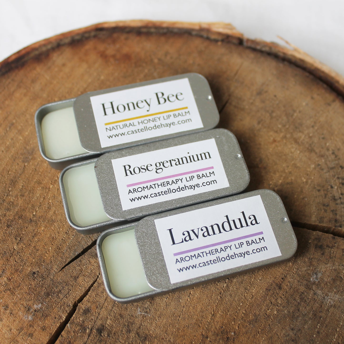 Honey Bee, Rose Geranium, Lavender lip balms on a wooden tray