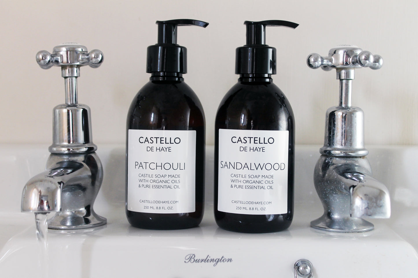 Patchouli and Sandalwood liquid castile soap together between two taps on a sink