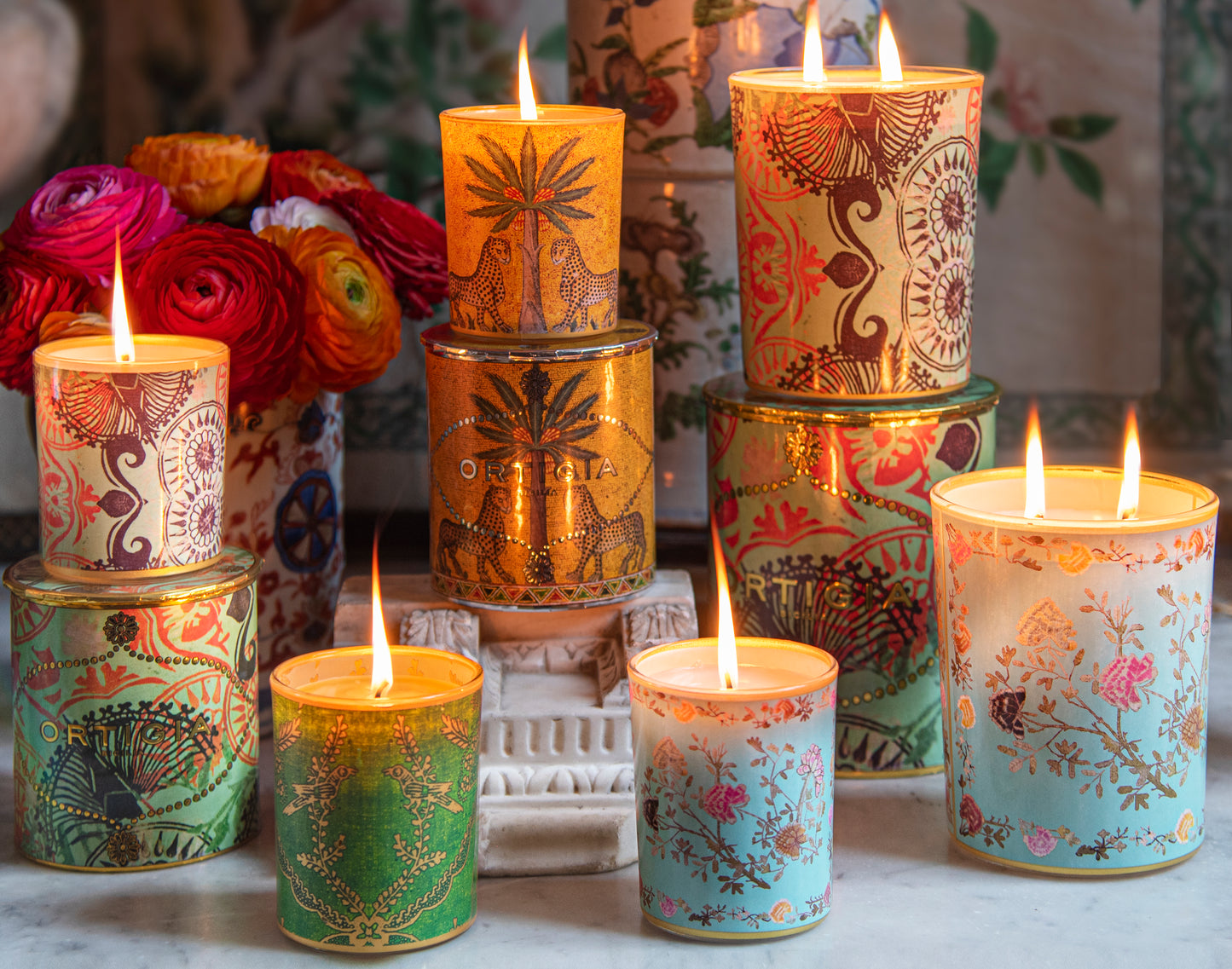 Group of Ortigia candles with vase of flowers in the background