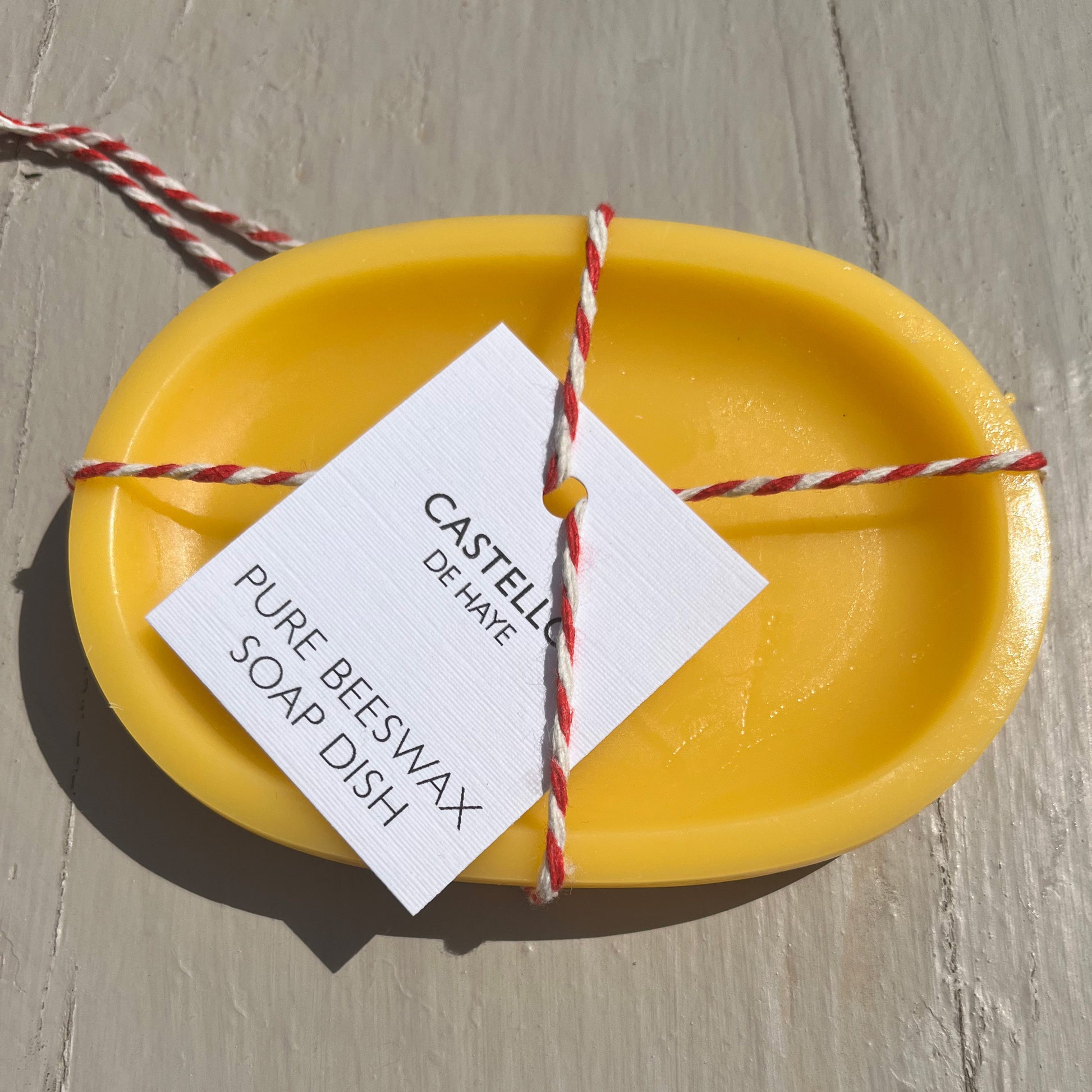 Yellow soap dish with a label on a wooden surface