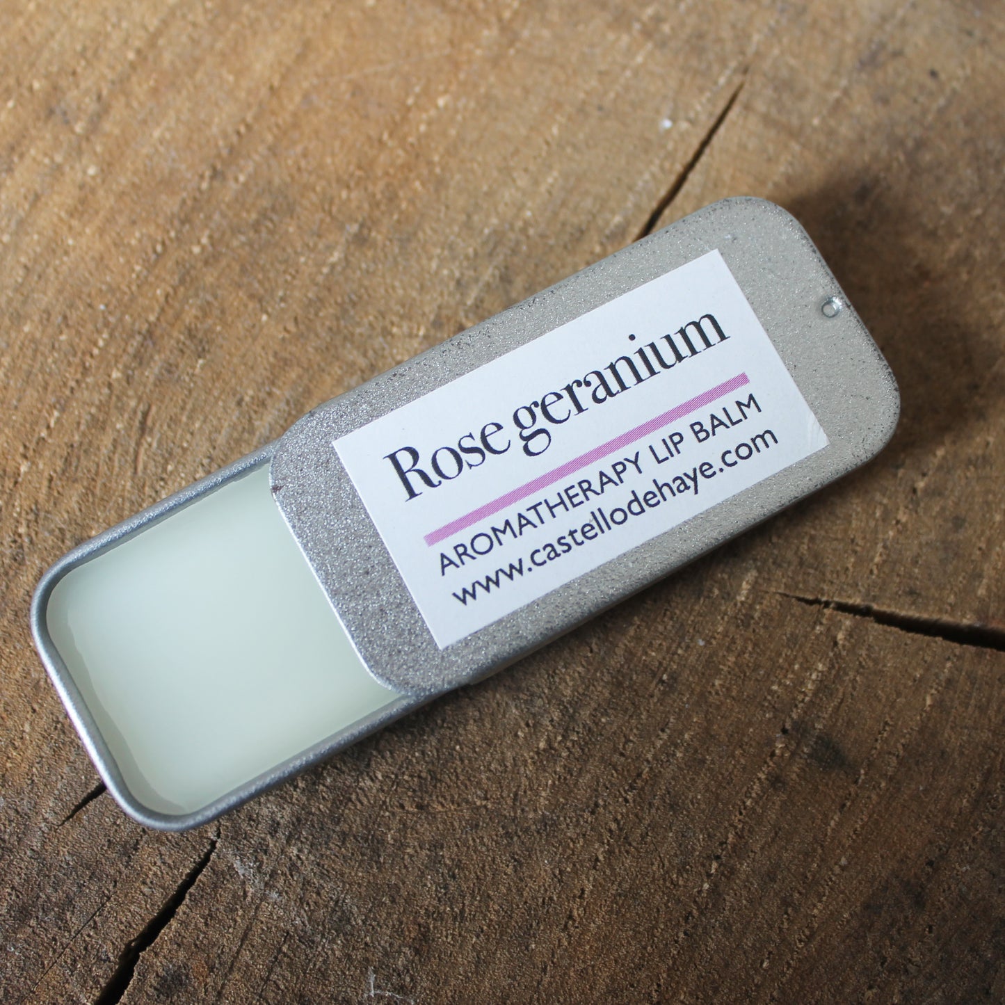 Rose Geranium aromatherapy lip balm in slide tin on wooden background