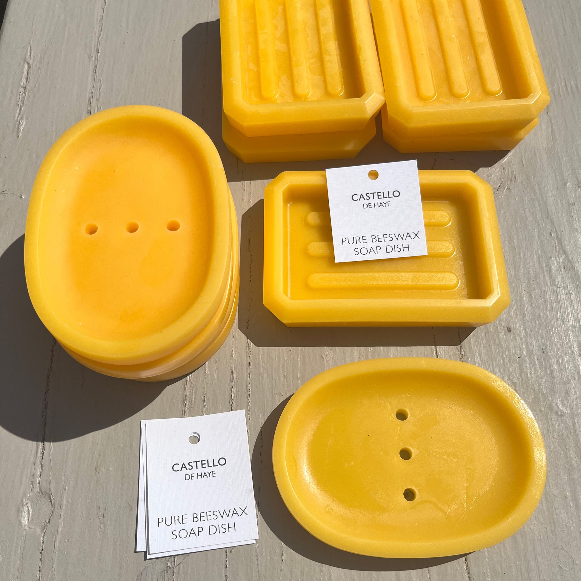 Yellow pure beeswax soap dishes on a wooden surface with labels.