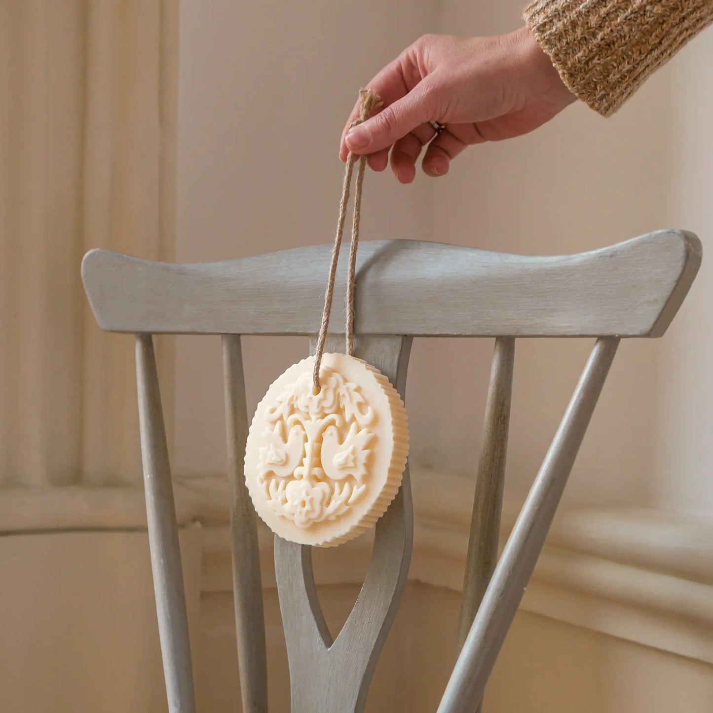 Castelbel Lovebirds Cedar & Rose Soap on Rope, hand holding soap bar in a softly lit indoor setting