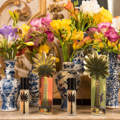 Ortigia Sicilia Perfume_Oil_Lifestyle two perfume oils with vases of flowers in the background