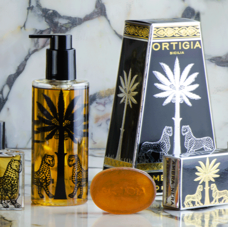 Collection of Ortigia perfume bottles on a marble surface with decorative elements.
