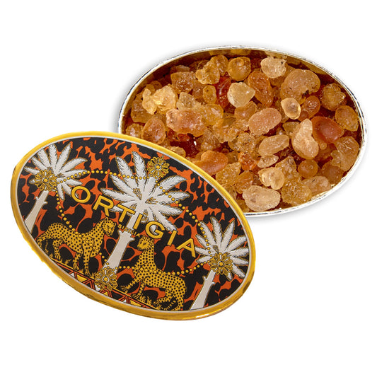 Decorative tin filled with amber-colored stones, featuring a decorative lid with 'Optica' branding.