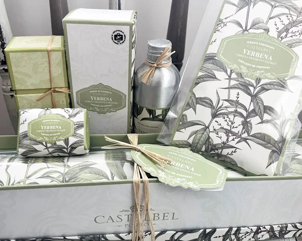 Collection of Castelbel Verbena products including soap, candles, and boxes on a white surface with botanical design.