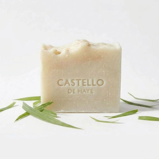 Natural cream Castello de Haye citronella soap bar with green citronella leaves on a white background