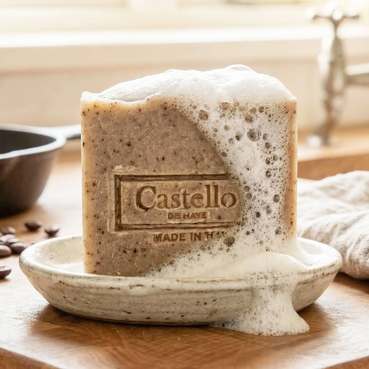 Coffee soap bar with rich lather on a ceramic dish, surrounded by coffee beans