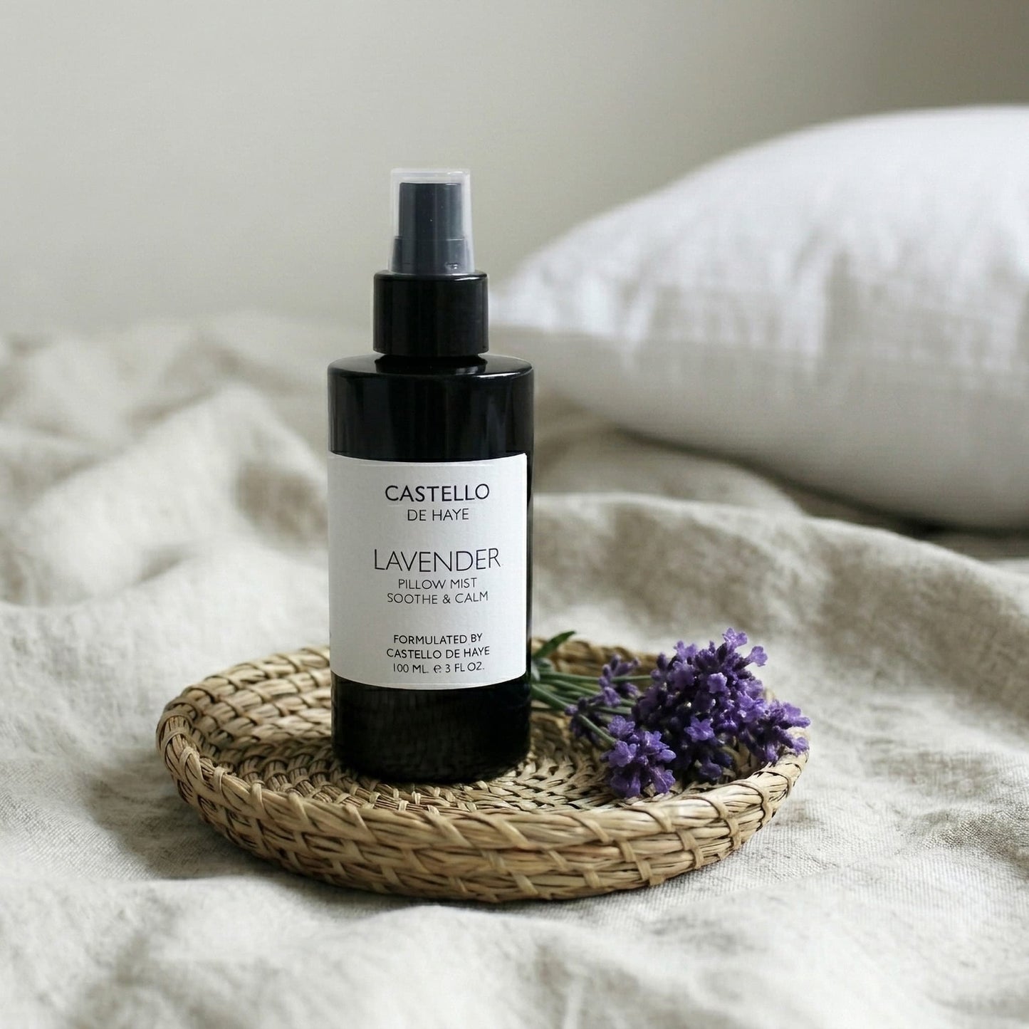 Lavender Pillow Mist on a woven tray with lavender sprigs on a linen bed