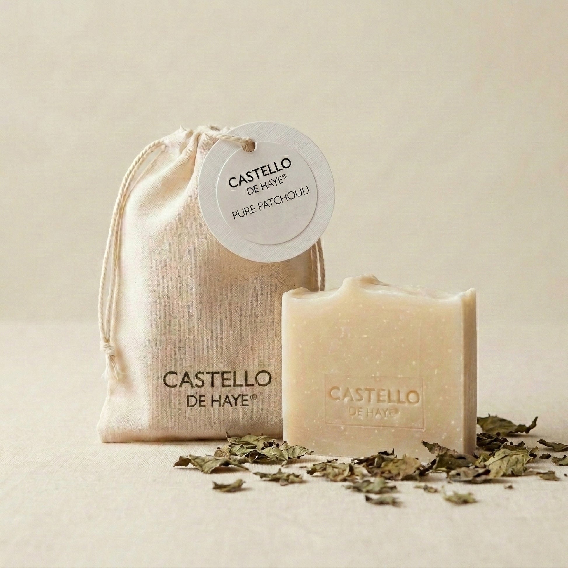 Pure patchouli soap bar with scattered fresh patchouli leaves – natural artisan soap by Castello de Haye