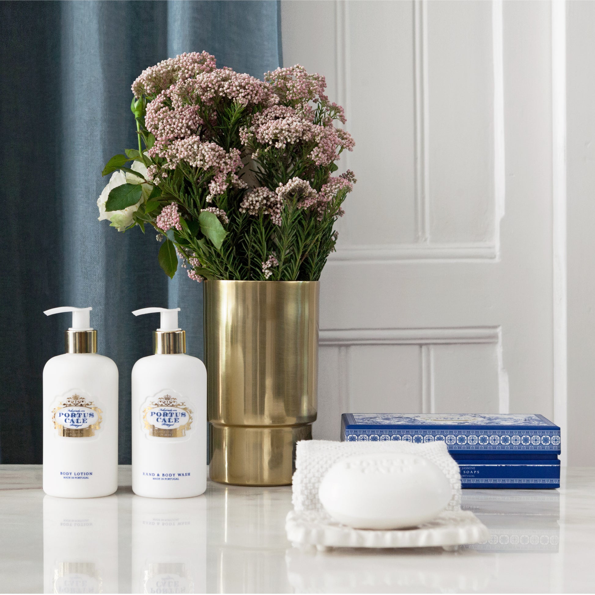 Portus cale body care with soap on a soap dish with gold vase and flowers in the background