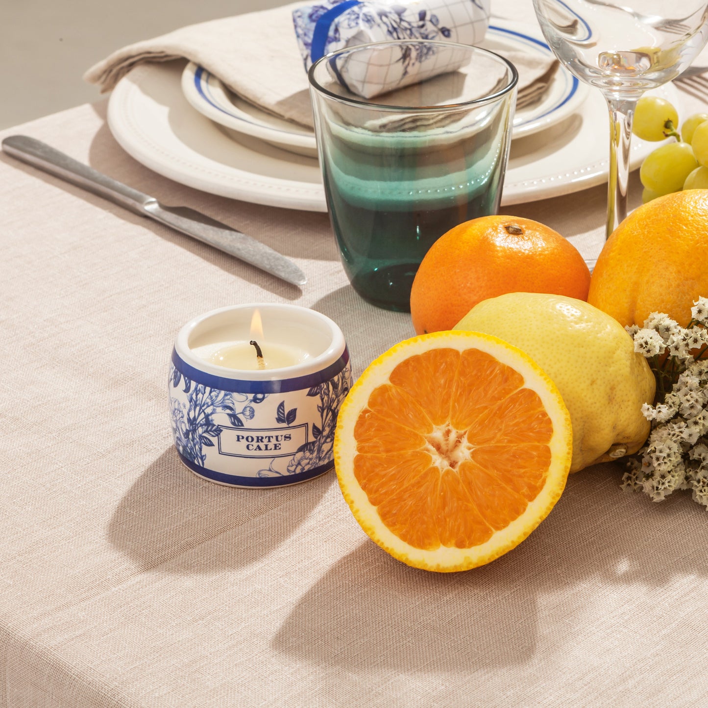 Portus Cale candle in ceramic pot on a dinner table with oranges and lemons