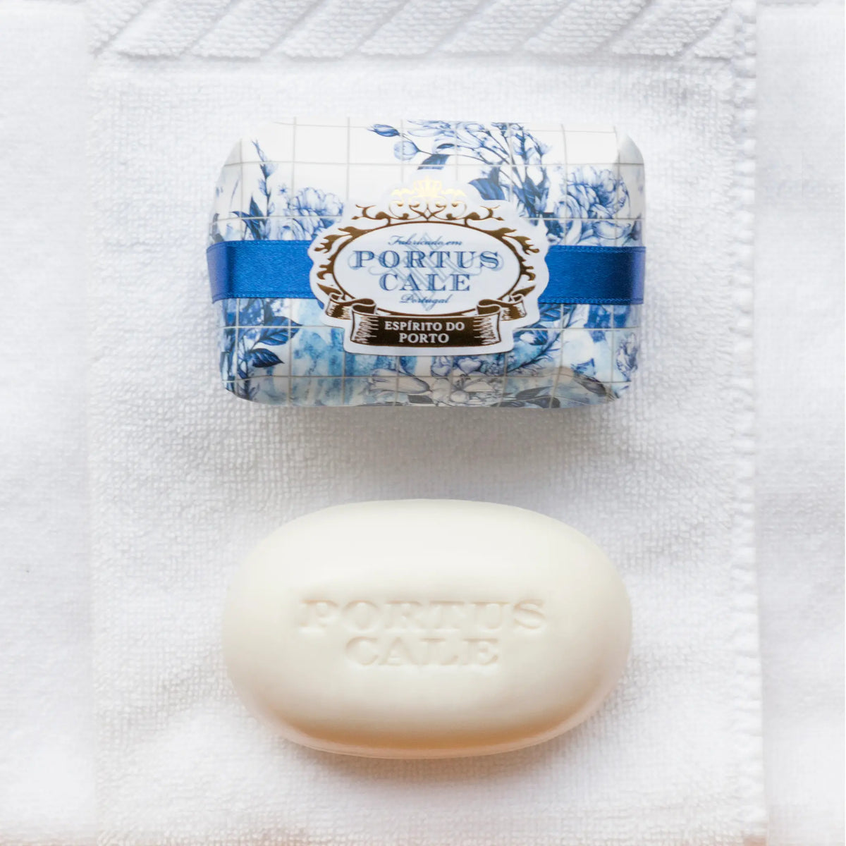 Portus Cale Gold & Blue 150g soap bar in floral wrapping, beside the unwrapped white oval soap
