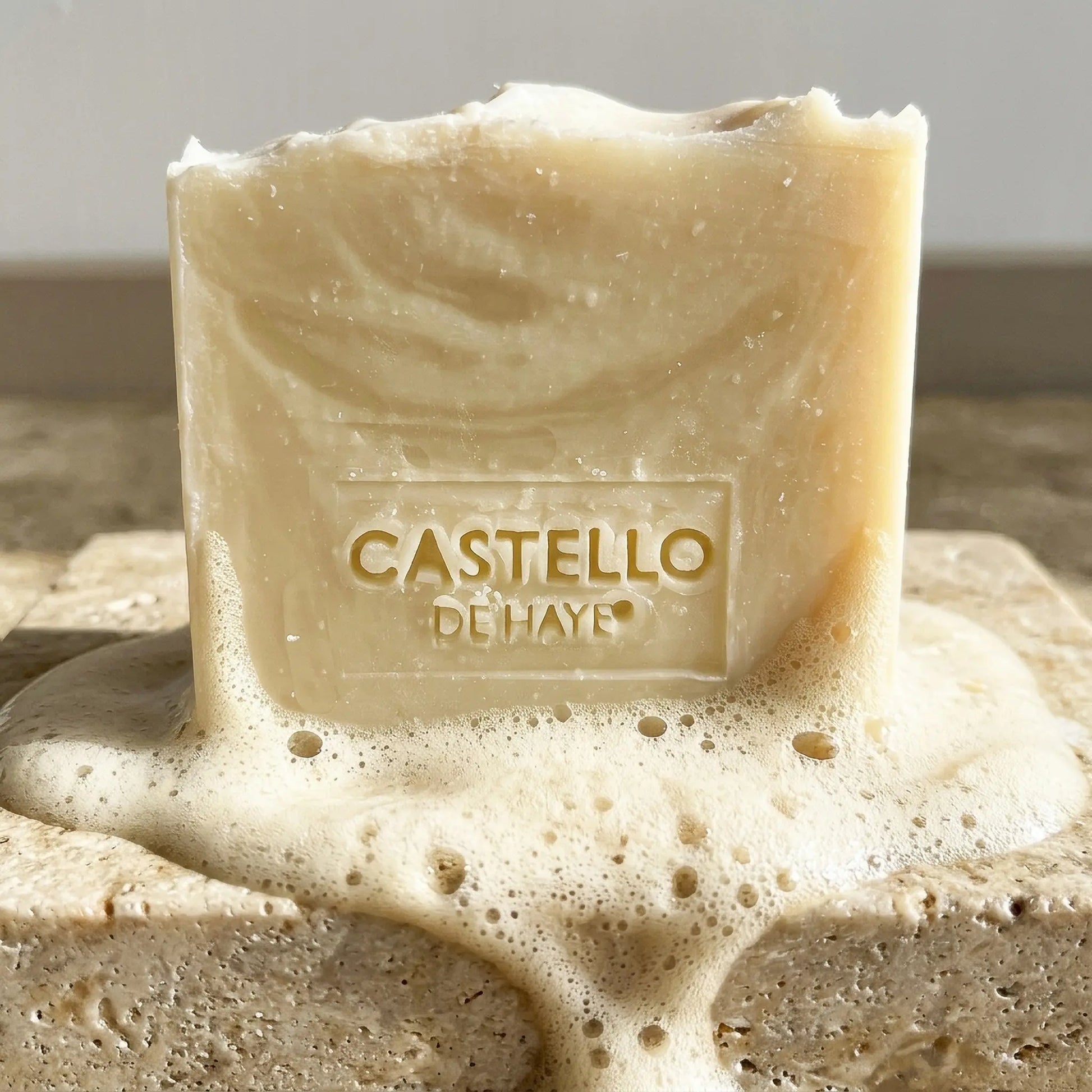 Pure olive unscented soap bar 200g, with soap suds on a stone soap dish