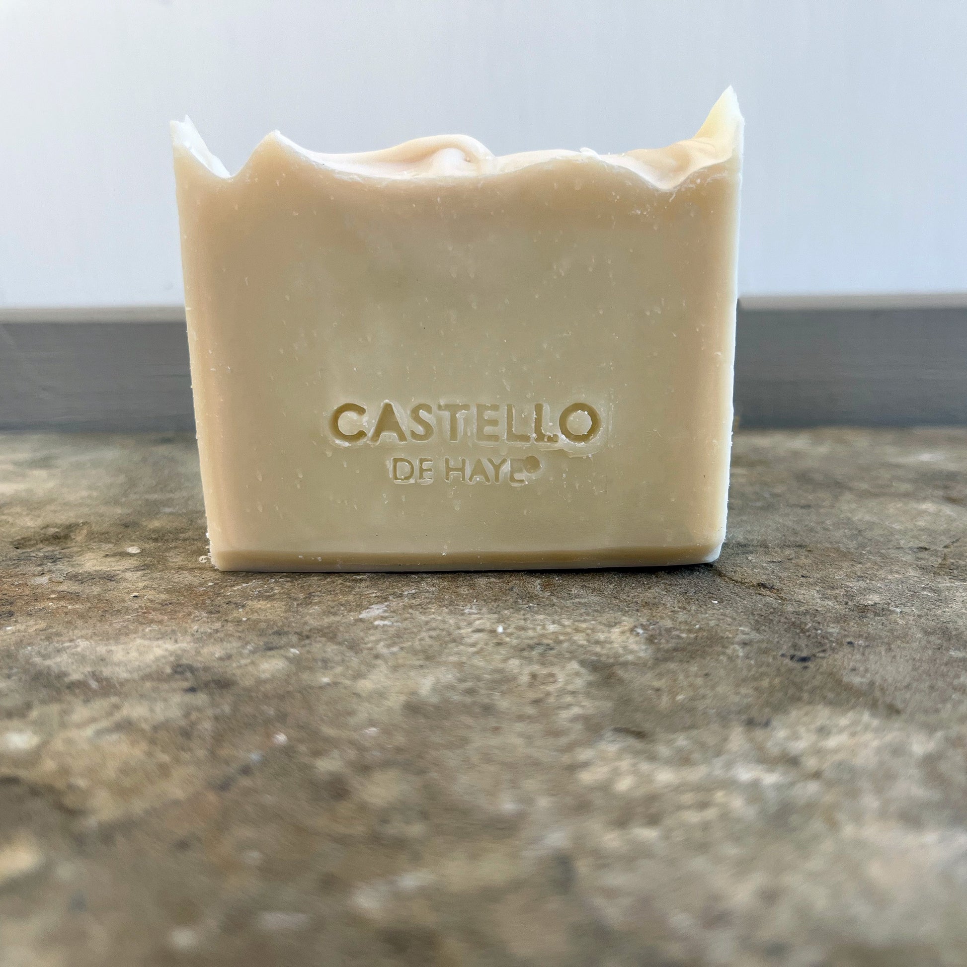 Unwrapped 200g patchouli soap bar with imprinted design resting on a dark slate surface