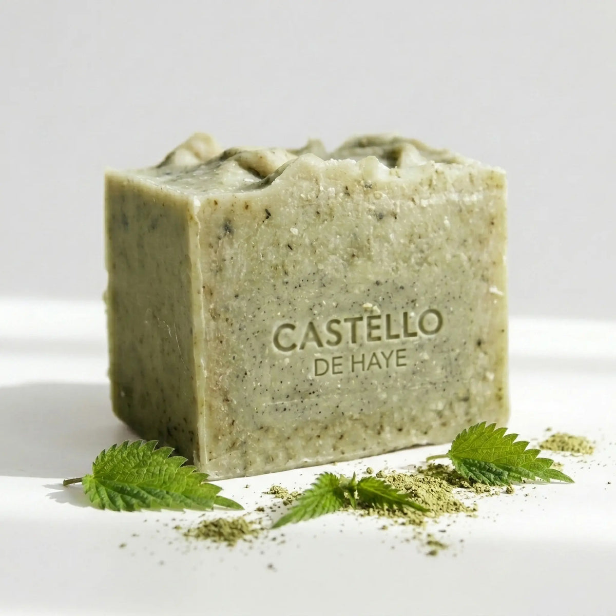 Castello de Haye Wild Nettle soap bar 200g, natural green handmade bar with Castello stamp, fresh nettle leaves scattered around the base, white background